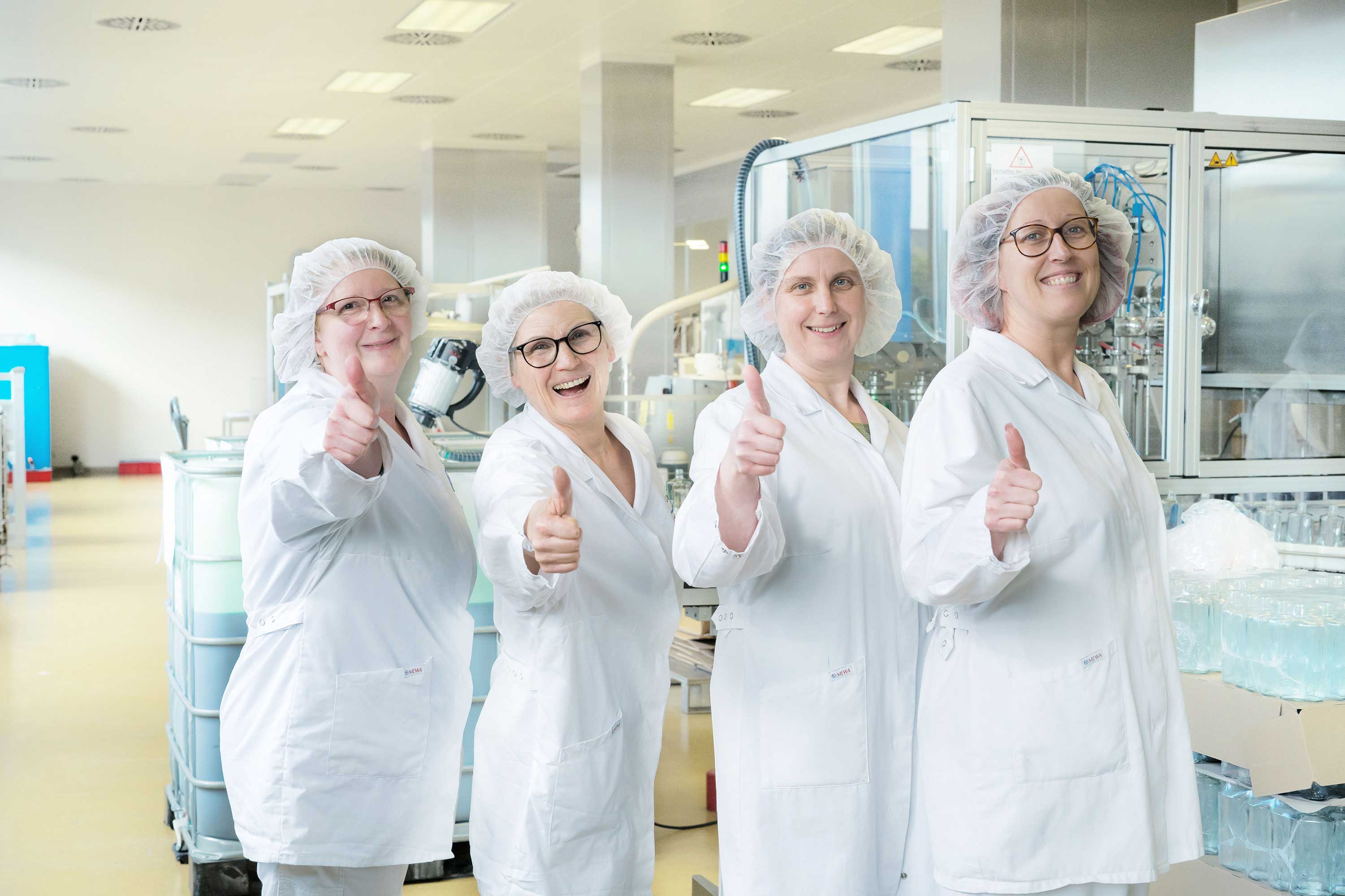 Mitarbeiterinnen lachen und heben Daumen hoch